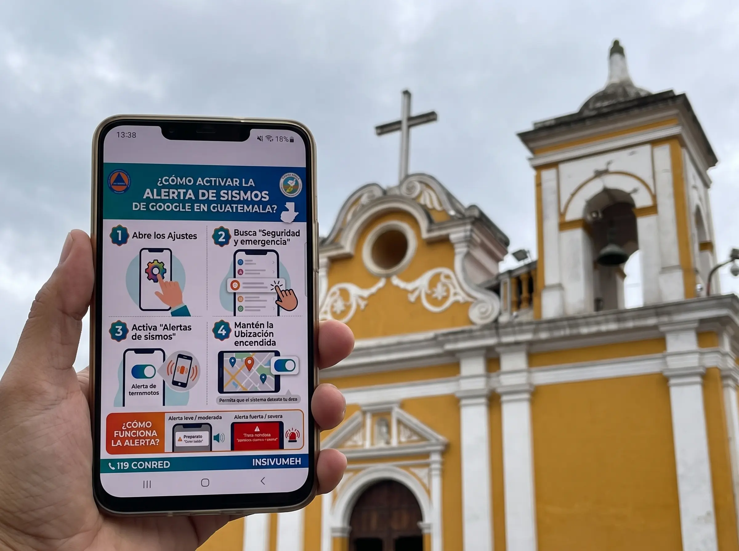 Teléfono móvil mostrando una notificación del sistema de alerta de terremotos frente a una iglesia en Guatemala.