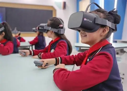 Niños en un salón de clases usando visores de realidad virtual Pico y controles manuales para aprendizaje inmersivo.